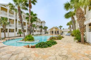 a courtyard with palm trees and a swimming pool at Corpus Christi Condo with Community Pool, Near Beach in Padre Island