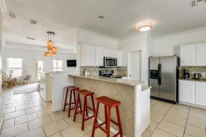 a kitchen with white cabinets and bar stools at Corpus Christi Condo with Community Pool, Near Beach in Padre Island