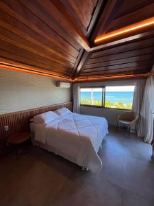 a bedroom with a large bed and a large window at Baixu Village in Arraial d'Ajuda