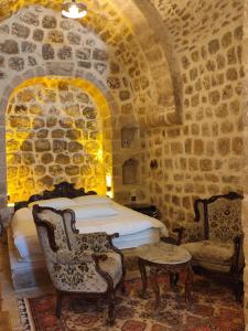 ein Schlafzimmer mit einem Bett und Stühlen in einer Steinmauer in der Unterkunft Rumet paşa konağı in Mardin