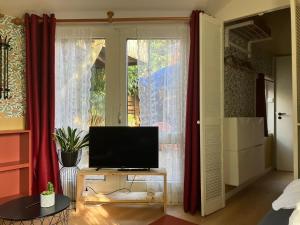 a living room with a television on a table in front of a window at B en B Op Steendam, Tuinkamer onder de appelboom in Steendam