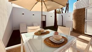 uma mesa de vidro com cadeiras e um guarda-sol em Click&Guest - Maspalomas Serenity Villa em San Bartolomé