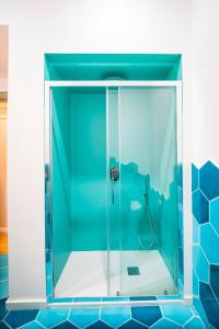 y baño con ducha de cristal y azulejos azules. en YourHome - Casa Cafiero, en Meta