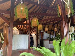 a room with a wooden ceiling with chandeliers and plants at Kohtao Heritage Hideaway in Ko Tao