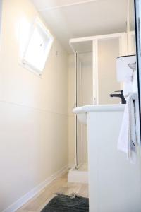 uma casa de banho branca com um lavatório e um espelho em House on wheels em Karterólion