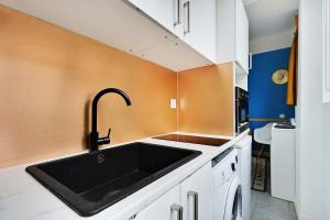 a kitchen with a black sink and orange wall at Cosy studio - Belleville in Paris