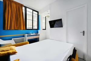 a bedroom with a white bed and a television at Cosy studio - Belleville in Paris