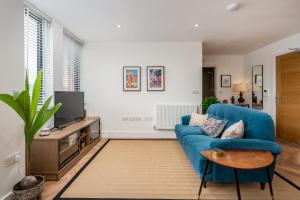 sala de estar con sofá azul y TV en Stylish Spacious Apartment in Central Windsor en Windsor
