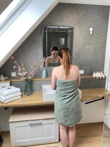 a woman in a green dress standing in front of a bathroom sink at Ferienwohnung Kellerer 2 in Waischenfeld