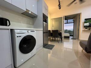uma cozinha com uma máquina de lavar roupa e uma sala de estar em Modern luxury Home at The Shore by Mihome em Kota Kinabalu