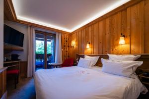 a bedroom with a large white bed with wooden walls at Relais et Châteaux - Les Bas-Rupts in Gérardmer
