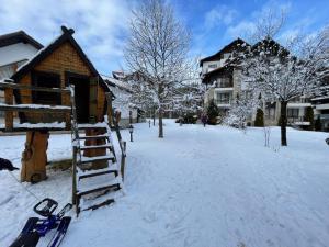 a snow covered street with a house and skis at Cozy Mountain Apartment in Borovets