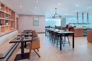 AC Hotel by Marriott San Jose Escazu في سان خوسيه: مطبخ به طاولات سوداء وكراسي في الغرفة