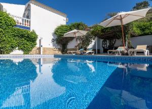 a swimming pool with chairs and umbrellas next to a building at Campo Agave Luxury Tents in Sayalonga