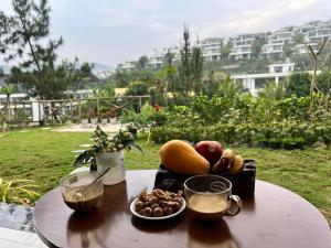 a table with a plate of fruit and drinks on it at Ivory Mountain Villa in Hòa Bình
