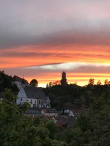 una puesta de sol sobre una ciudad con una torre de reloj en una colina en Ferienwohnung Kellerer 2 en Waischenfeld