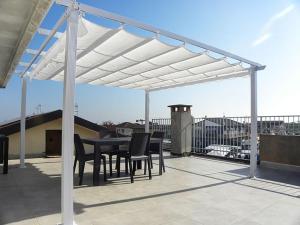 a patio with a table and chairs under a white pergola at Casa Cicolani in Scardovari