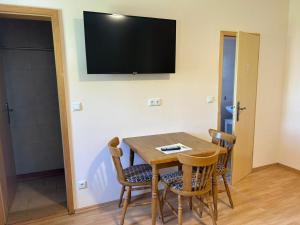 a room with a table and chairs with a television on the wall at Ferienwohnung Falkeneck in Lautertal