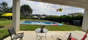 a patio with a table and chairs and a pool at T2 avec Piscine exclusive in Bourg-Saint-Bernard