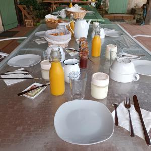 una mesa con platos blancos y botellas de zumo de naranja en Baladous, en Montgaillard-de-Salies