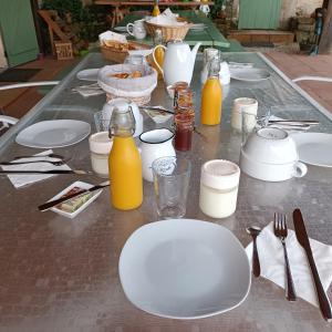 a table with white plates and bottles of orange juice at Baladous in Montgaillard-de-Salies