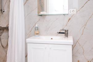 La salle de bains est pourvue d'un lavabo blanc et d'un rideau de douche. dans l'établissement Appartement Babette, à Zandvoort