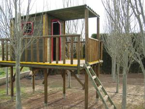 uma casa de jogos de madeira com uma escada num parque em Cortijo Villarosa em Benablón