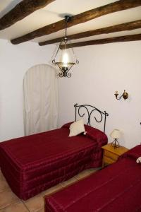 um quarto com 2 camas vermelhas e um lustre em Cortijo Villarosa em Benablón