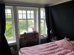 a bedroom with a pink bed and two windows at Unik eiendom i Gjøvik sentrum in Gjøvik