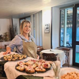 Una donna in piedi dietro un tavolo con un vassoio di ciambelle di Hotel Bel Sogno a Rimini