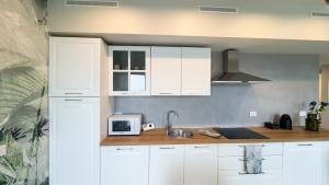 a kitchen with white cabinets and a sink at Farmont Seafront Acquamarine Suite by CaSa Check in Chioggia