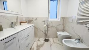 a white bathroom with a sink and a toilet at Farmont Seafront Acquamarine Suite by CaSa Check in Chioggia