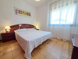 um quarto com uma cama branca e uma janela em HomeHolidaysRentals Owen - Costa Barcelona em Pineda de Mar
