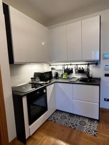 uma cozinha com armários brancos e um forno de fogão preto em Miro Home II em Roma