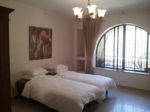two beds in a bedroom with a window and a chandelier at Glows in Jerusalem