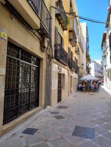 una calle vacía con gente sentada bajo un paraguas en Apartamento Maestra, en Jaén