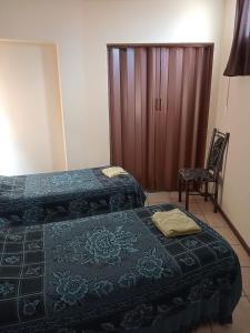 1 dormitorio con 2 camas, silla y armario en Departamentos Romano en Mendoza