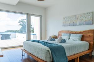 a bedroom with a large bed and a large window at Azores Dreams - Sea View House in São Roque +42 photos