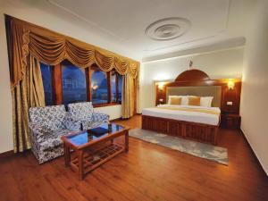 a bedroom with a bed and a couch and a table at Hotel Surya International - Manali in Manāli