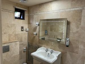 a bathroom with a sink and a mirror at Oakwood Bed and Breakfast Heathrow in Hillingdon