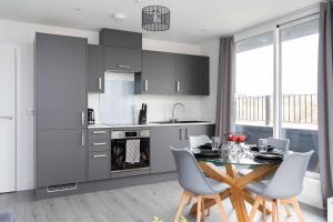 a kitchen with a table and chairs and a kitchen with gray cabinets at Weekly Monthly Discount Free Parking Sleeps 3 in Hemel Hempstead