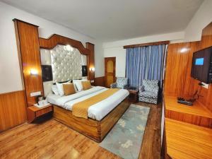 a bedroom with a large bed and a television in it at Hotel Surya International - Manali in Manāli