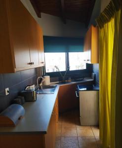 eine Küche mit Holzschränken, einem Waschbecken und einem Fenster in der Unterkunft Lenia's seaside apartment in Faraí