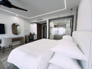 biała sypialnia z dużym białym łóżkiem z poduszkami w obiekcie Bellagio Beach Resort & Spa w mieście Hurghada