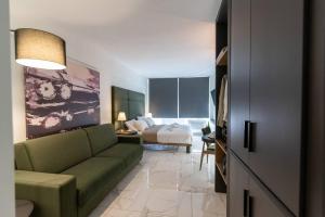 a living room with a green couch and a bed at MG Sapphire Junior Premium Suite in Thessaloniki