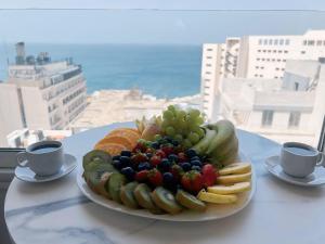 een schaal fruit op een tafel met twee kopjes koffie bij Ny Suites in Beiroet