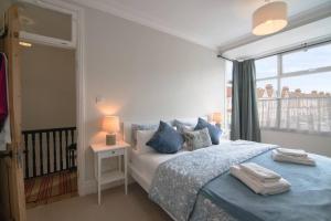um quarto com uma cama com almofadas azuis e uma janela em Pass the Keys Cosy Stylish house near Southend em Southend-on-Sea