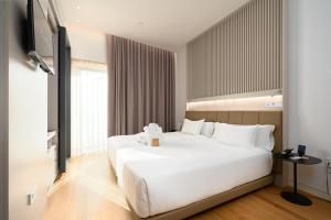 um quarto com uma grande cama branca e uma televisão em Hotel Kivir em Sevilha