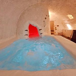 a large pool of blue water in a room with a fireplace at LE GRAND LOGIS, chambre Santorin avec spa privatif 