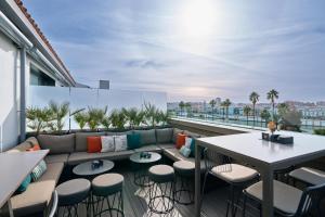 a rooftop patio with a couch and tables and chairs at Hotel Kivir in Seville